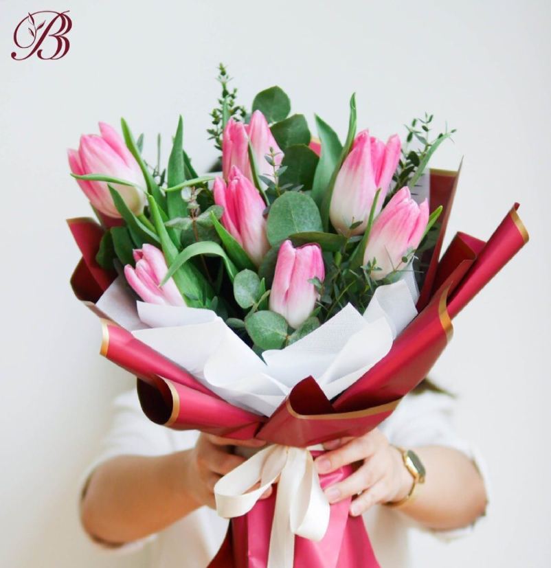 Pink tulip bouquet held toward the camera